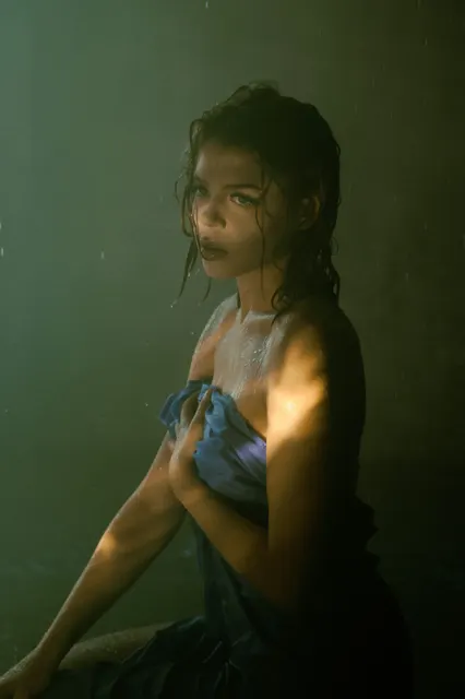 This shot masterfully uses a single hard, warm light source to sculpt the subjec