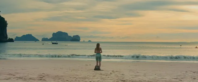 This wide shot beautifully captures a solitary figure on a vast beach, gazing ou
