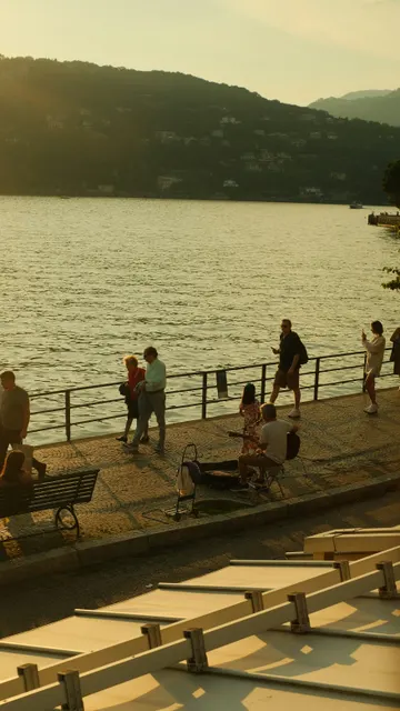 An elevated high-angle shot captures a sun-drenched lakeside promenade during la